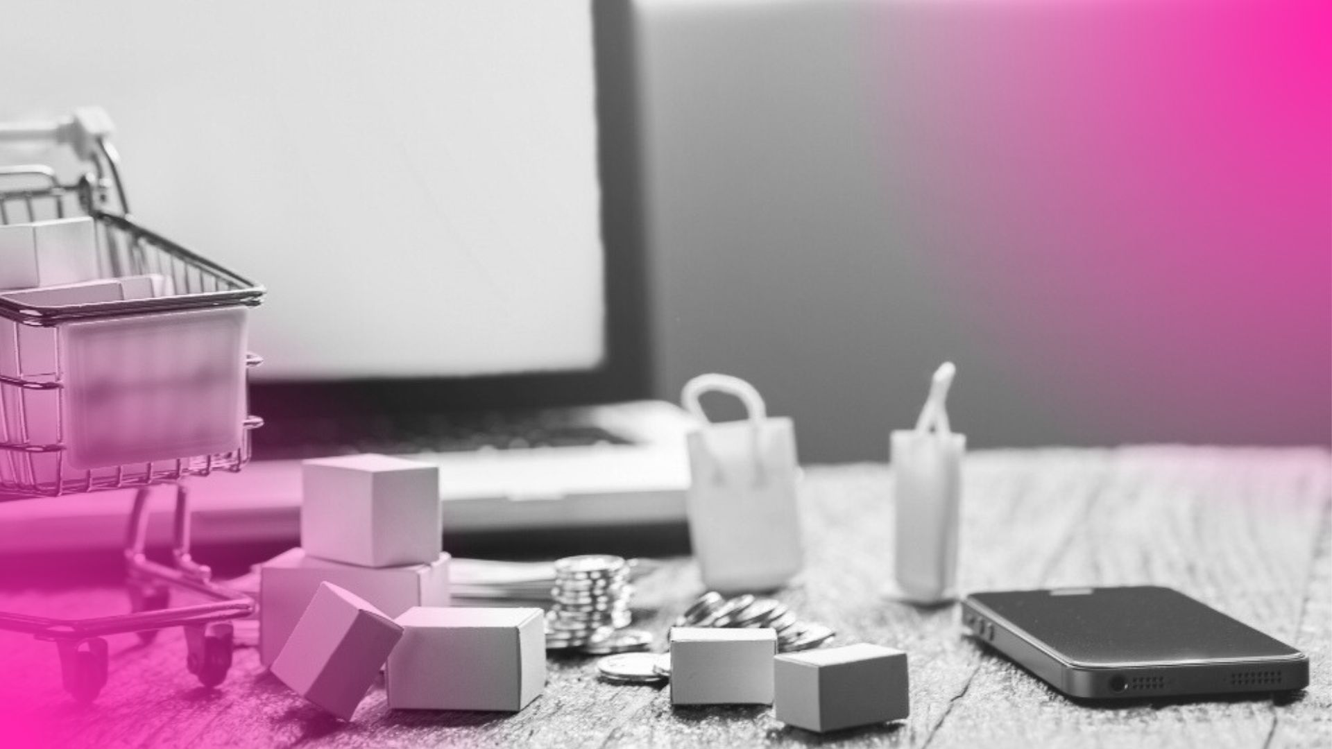 Mini carrinho, caixas e moedas sobre mesa com notebook ao fundo, simbolizando ferramentas de venda para controle financeiro e operações online.