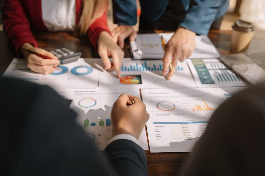 Equipe revisando relatórios e gráficos em reunião de análise de concorrência para decisão de portfólio em marketplace.