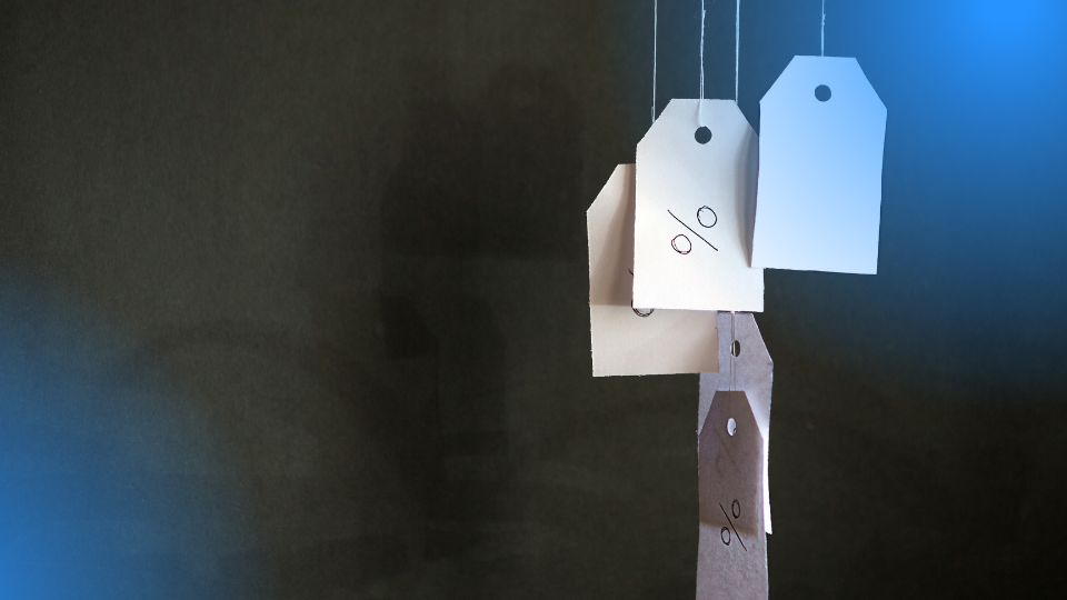 Etiquetas de pre&ccedil;o com s&iacute;mbolo de percentual penduradas, representando uma estrat&eacute;gia de pre&ccedil;o