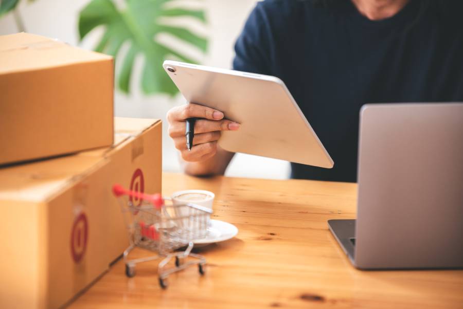 Seller com tablet e caixas de envio na mesa, representando custo e precificação