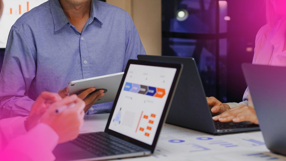 Equipe usando laptops e tablet em reunião de negócios analisando ferramentas de precificação para marketplace